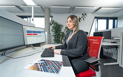 Mitarbeiterin sitzt am Schreibtisch und schaut in ihren Bildschirm.jpg